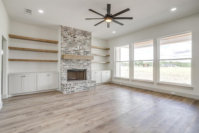 unfurnished living room with plenty of natural light, light hardwood / wood-style flooring, ceiling fan, and a brick fireplace