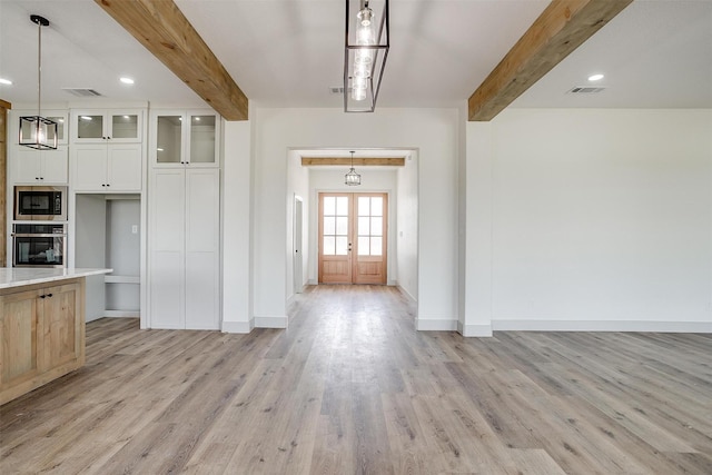 kitchen featuring visible vents, glass insert cabinets, white cabinets, built in microwave, and oven