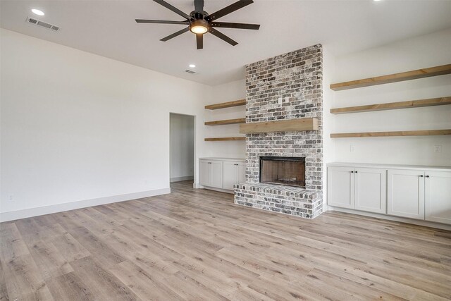 living room featuring wood-type flooring, a fireplace, and ceiling fan