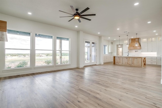 unfurnished living room featuring light wood-type flooring, ceiling fan, and sink