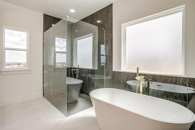 bathroom featuring a wealth of natural light, a shower stall, tile walls, and a freestanding bath