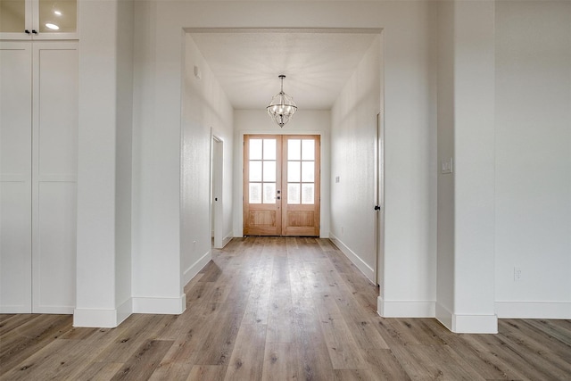 entryway with an inviting chandelier, light hardwood / wood-style flooring, and french doors