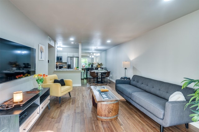 living room featuring a chandelier and light hardwood / wood-style flooring