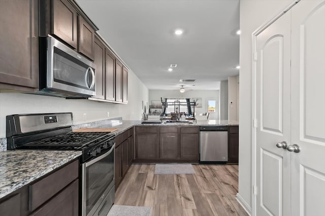 kitchen featuring light stone counters, stainless steel appliances, light wood-type flooring, and kitchen peninsula