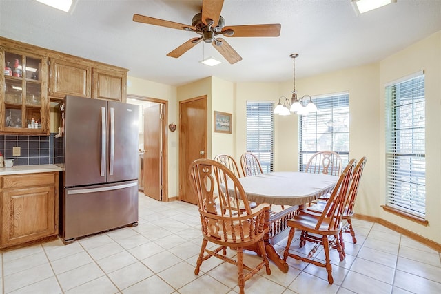 tiled dining space featuring ceiling fan with notable chandelier and a textured ceiling