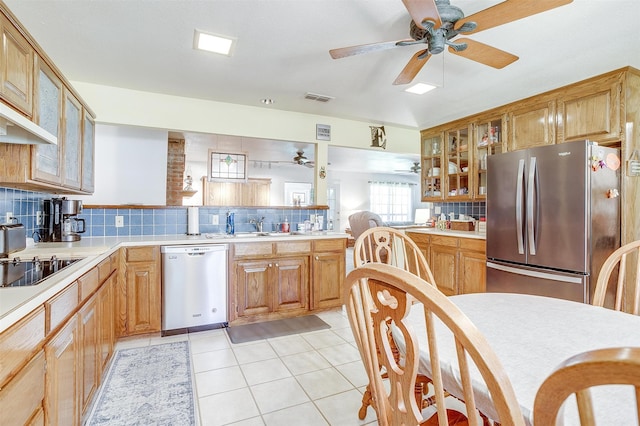 kitchen featuring light tile patterned floors, appliances with stainless steel finishes, kitchen peninsula, ceiling fan, and decorative backsplash