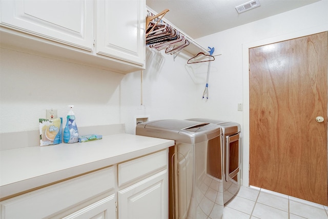 laundry room featuring light tile patterned flooring, cabinets, and washing machine and dryer