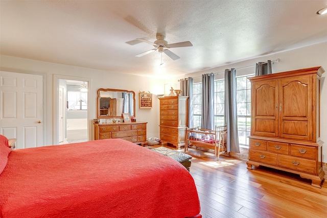 bedroom featuring ceiling fan, light hardwood / wood-style floors, a textured ceiling, and ensuite bathroom