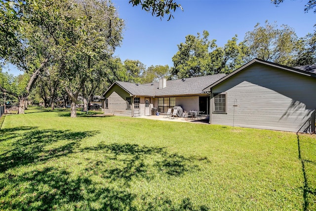 back of house with a lawn and a patio