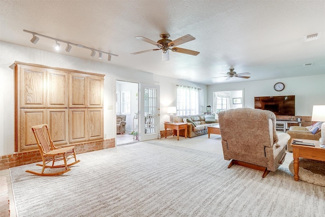 carpeted living room featuring track lighting, a textured ceiling, and ceiling fan