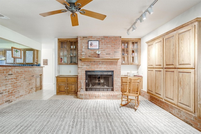 tiled living room featuring a textured ceiling, brick wall, ceiling fan, and a brick fireplace