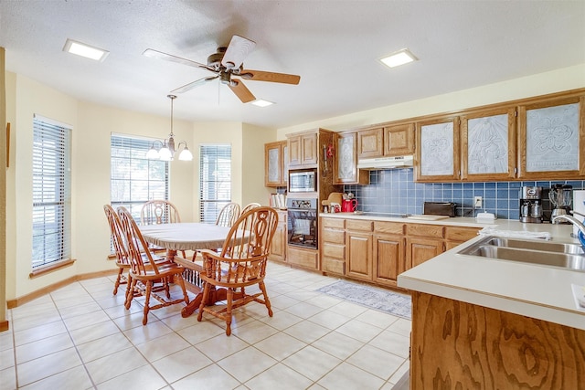 kitchen with ceiling fan with notable chandelier, oven, sink, hanging light fixtures, and stainless steel microwave