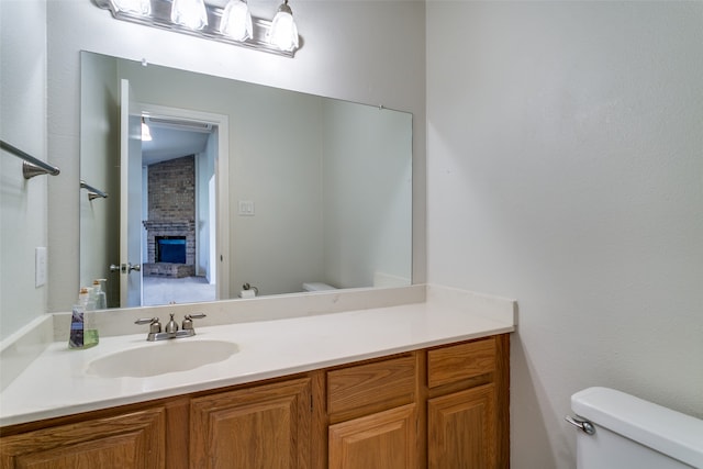 bathroom featuring a fireplace, vanity, and toilet