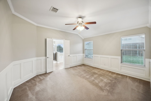 carpeted spare room with lofted ceiling, a wealth of natural light, ornamental molding, and ceiling fan