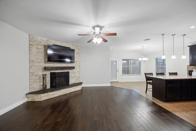 living room with a stone fireplace, hardwood / wood-style floors, and ceiling fan with notable chandelier