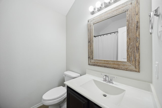 bathroom with vanity, toilet, and lofted ceiling