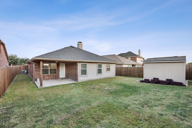 rear view of property featuring a shed, a yard, a patio, and central AC