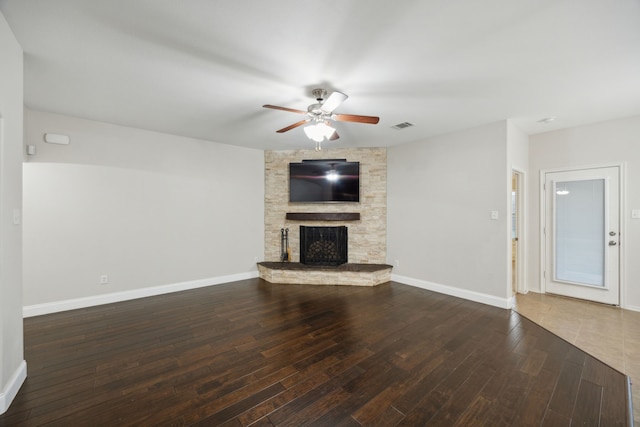 unfurnished living room featuring a fireplace, ceiling fan, and dark wood-type flooring