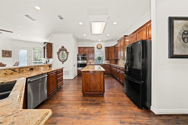 kitchen with appliances with stainless steel finishes, dark hardwood / wood-style flooring, a kitchen island, and light stone counters