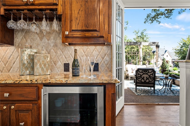 kitchen with backsplash, wine cooler, light stone counters, and dark wood-type flooring