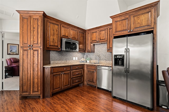 kitchen featuring light stone countertops, appliances with stainless steel finishes, dark hardwood / wood-style flooring, tasteful backsplash, and sink