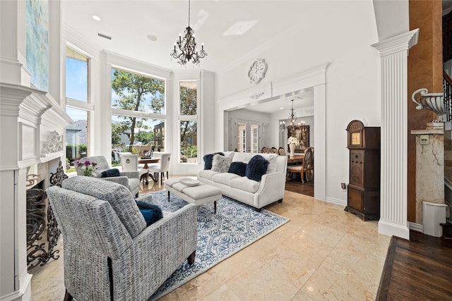 living room featuring decorative columns, a fireplace, plenty of natural light, and an inviting chandelier