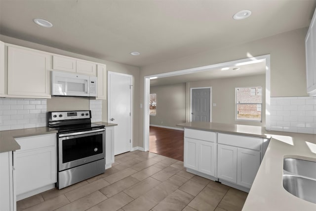 kitchen featuring sink, white cabinetry, tasteful backsplash, stainless steel electric range oven, and light wood-type flooring