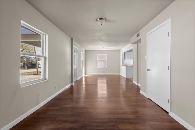 hallway featuring a healthy amount of sunlight and dark hardwood / wood-style floors