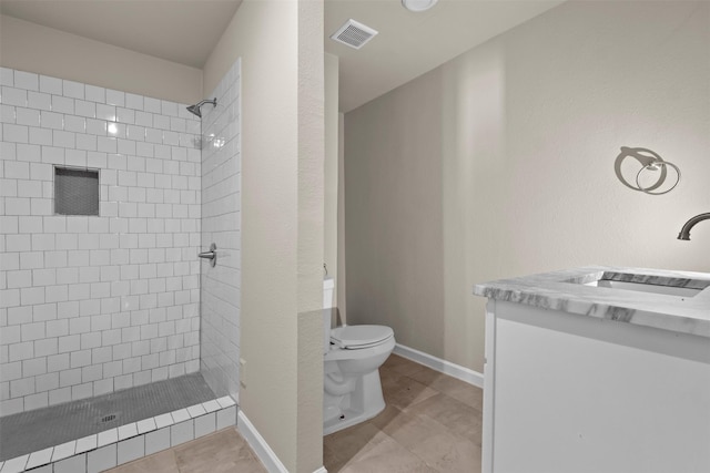 bathroom featuring vanity, a tile shower, and toilet