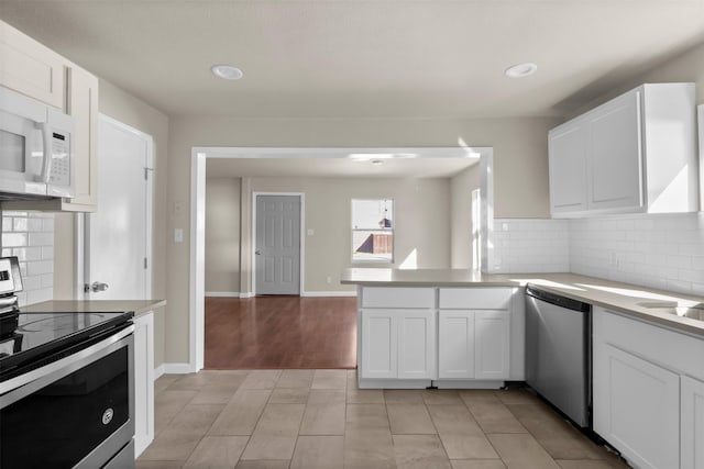 kitchen featuring light tile patterned floors, appliances with stainless steel finishes, white cabinetry, tasteful backsplash, and kitchen peninsula