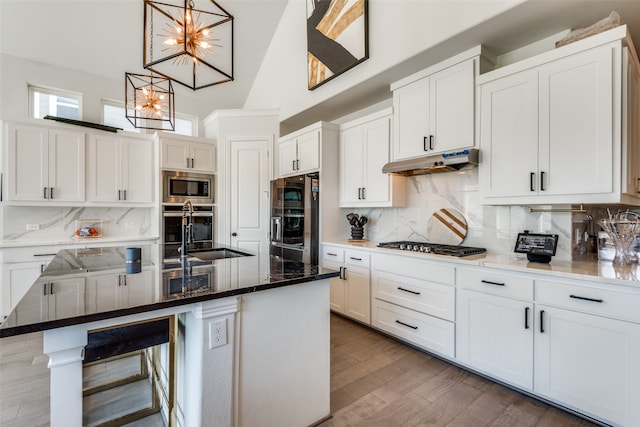 kitchen featuring appliances with stainless steel finishes, hardwood / wood-style flooring, a chandelier, and a kitchen island with sink