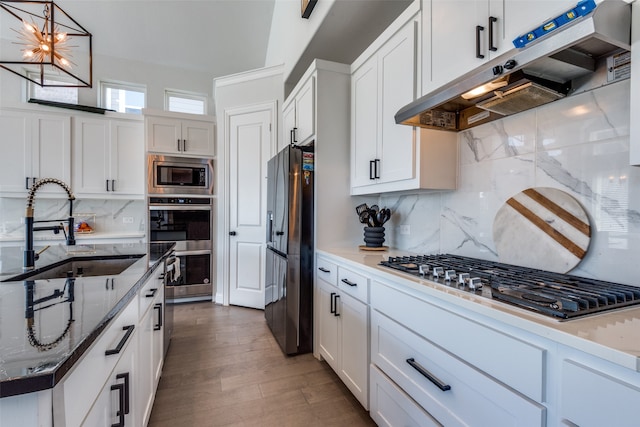 kitchen with backsplash, appliances with stainless steel finishes, white cabinetry, sink, and dark wood-type flooring