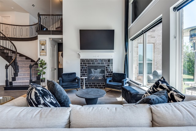 living room featuring wood-type flooring, a tile fireplace, and a high ceiling