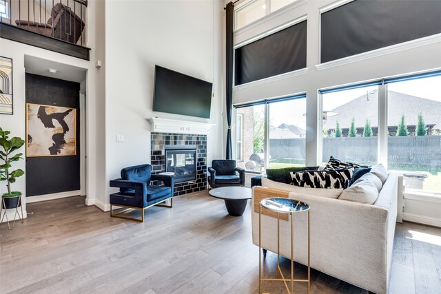 living room featuring a tiled fireplace, plenty of natural light, and hardwood / wood-style floors