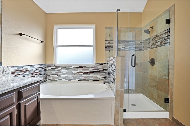 bathroom featuring shower with separate bathtub, vanity, and tasteful backsplash