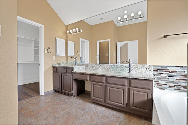 bathroom with vanity, lofted ceiling, a tub, backsplash, and hardwood / wood-style flooring