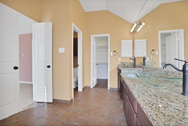 bathroom with vanity, lofted ceiling, toilet, and tile patterned floors