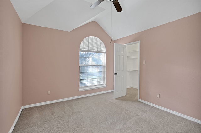 empty room with ceiling fan, lofted ceiling, and light carpet