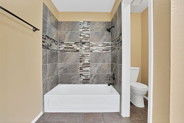 bathroom with tiled shower / bath, toilet, and tile patterned floors