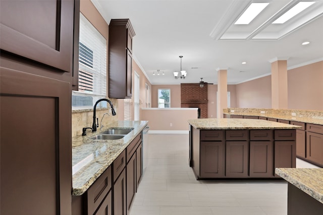 kitchen featuring light stone counters, decorative light fixtures, dark brown cabinetry, ornamental molding, and sink