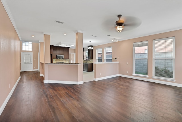 unfurnished living room with ornamental molding, dark hardwood / wood-style flooring, ceiling fan, and plenty of natural light