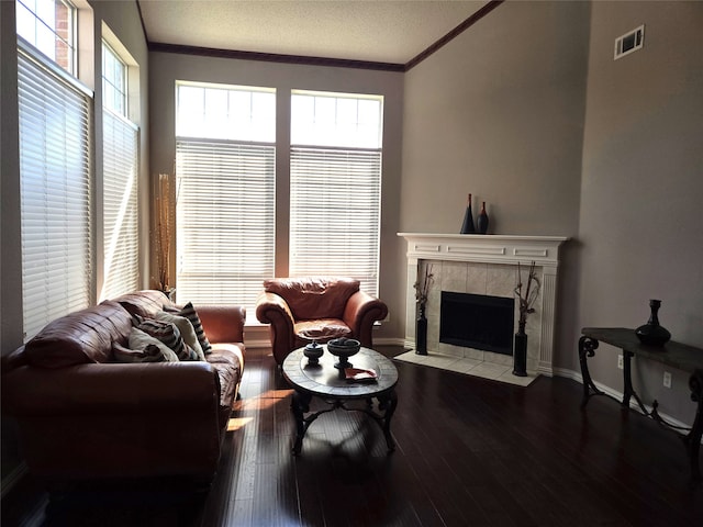 living room with a textured ceiling, crown molding, light wood-type flooring, and a tiled fireplace