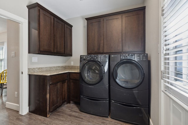 laundry area with washing machine and clothes dryer, dark hardwood / wood-style flooring, and cabinets