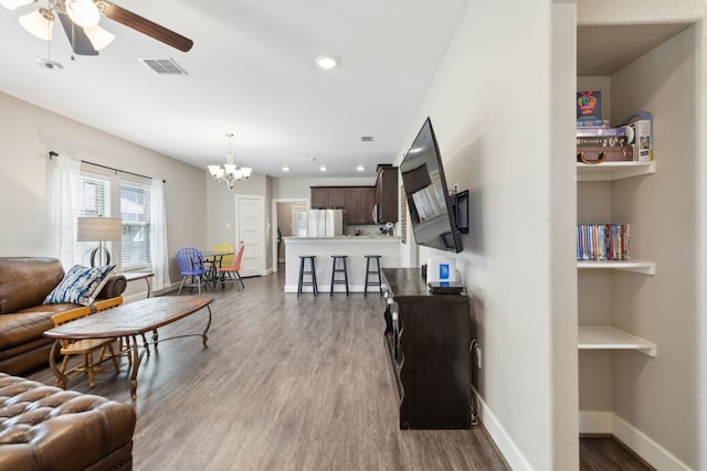 living room featuring ceiling fan with notable chandelier and light hardwood / wood-style flooring