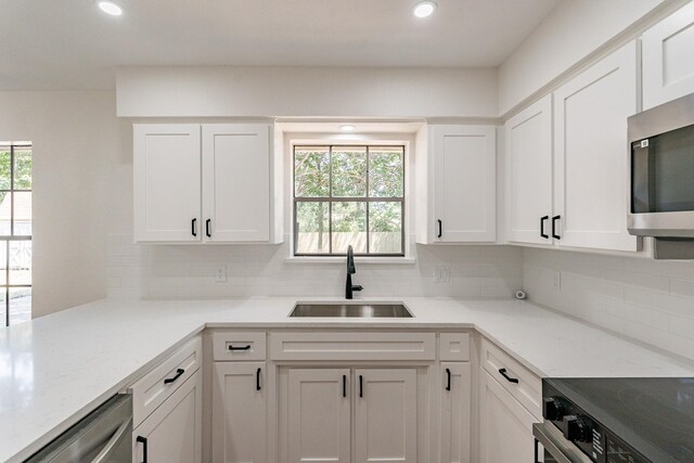 kitchen with white cabinets, appliances with stainless steel finishes, plenty of natural light, and sink