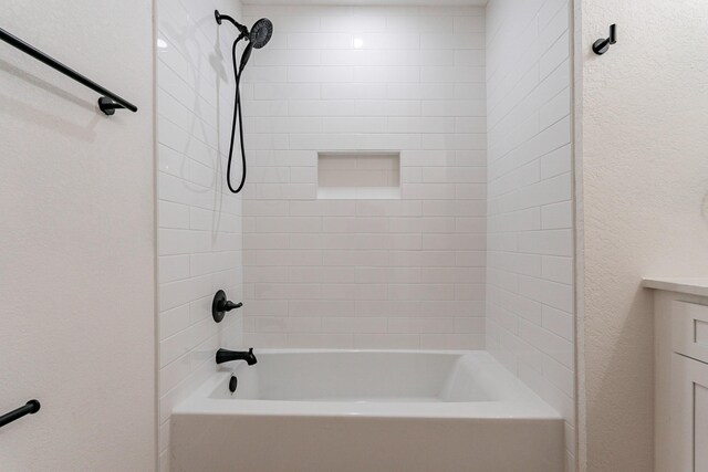 bathroom with tiled shower / bath and vanity