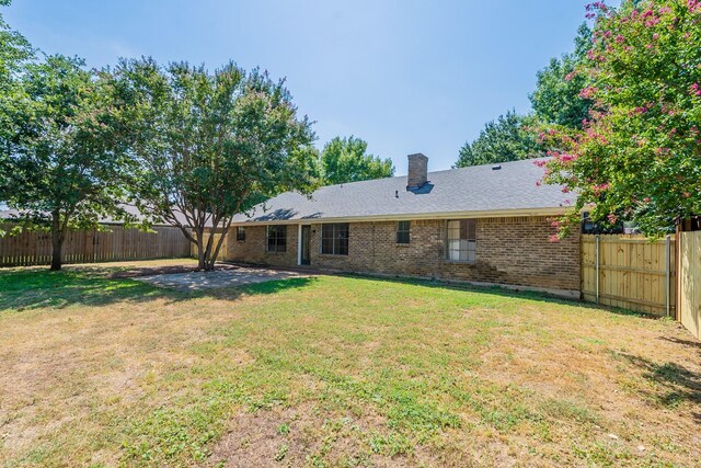 rear view of house with a lawn and a patio