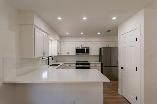 kitchen with stainless steel appliances, dark hardwood / wood-style flooring, white cabinetry, and sink