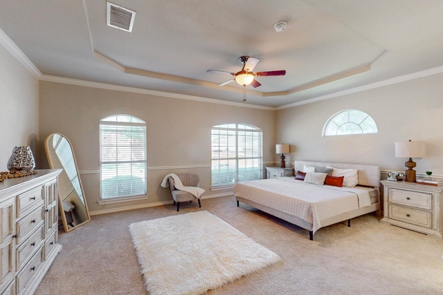 carpeted bedroom featuring a tray ceiling, ceiling fan, and multiple windows