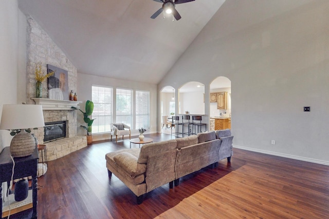 living room featuring high vaulted ceiling, ceiling fan, wood-type flooring, and a fireplace